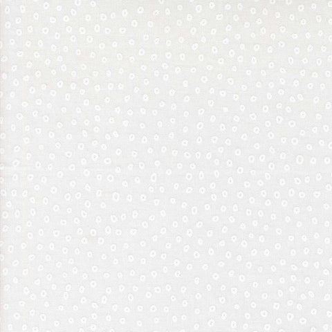 Patterned fabric with small white shapes on a light background