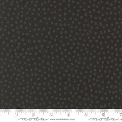 Patterned fabric with small gray shapes on a dark background with ruler