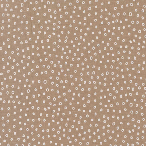 Patterned fabric with small white shapes on a beige background