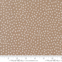 Patterned fabric with small white shapes on a beige background with ruler