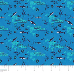 Pattern of sharks with 'Shark Week' text and logos on a blue background with ruler