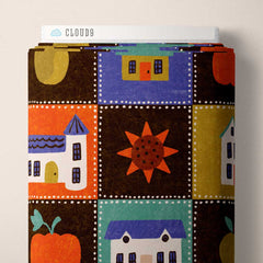 Halloween-themed design with a delightful array of motifs including pumpkins, sunflowers, and quaint houses, all set against a rich brown background with a playful dotted border framing each square on a fabric roll