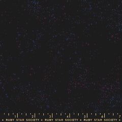 Pattern of multi-colored speckles on a black background with ruler