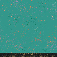 Pattern of multi-colored speckles on a teal background with ruler