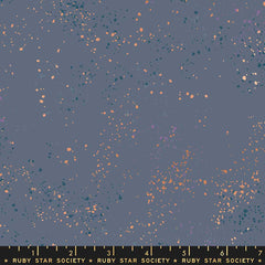 Pattern of multi-colored speckles on a dark blue background with ruler