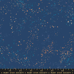 Pattern of multi-colored speckles on a blue background with ruler