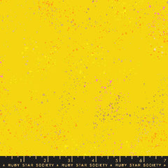 Pattern of multi-colored speckles on a yellow background with ruler
