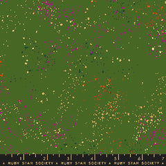 Pattern of multi-colored speckles on a green background with ruler
