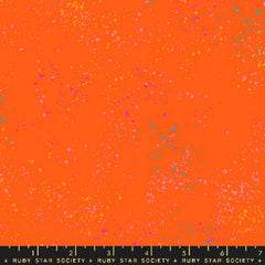 Pattern of multi-colored speckles on an orange background with ruler