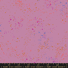 Pattern of multi-colored speckles on a light purple background with ruler