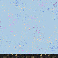 Pattern of multi-colored speckles on a light blue background with ruler