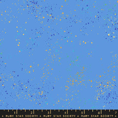 Pattern of multi-colored speckles on a blue background with ruler