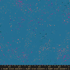 Pattern of multi-colored speckles on a blue background with ruler