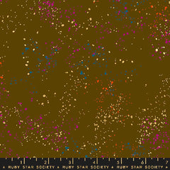 Pattern of multi-colored speckles on a brown background with ruler