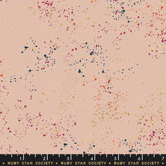Pattern of multi-colored speckles on a light pink background with ruler