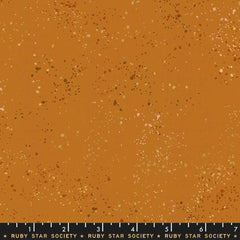 Pattern of multi-colored speckles on a light brown background with ruler