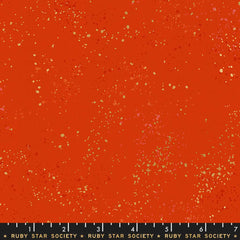 Pattern of multi-colored speckles on a red background with ruler