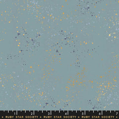 Pattern of multi-colored speckles on a light blue background with ruler