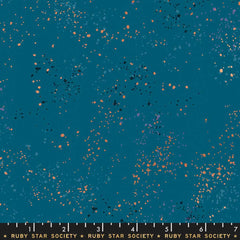 Pattern of multi-colored speckles on a teal background with ruler