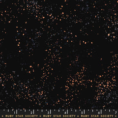Pattern of multi-colored speckles on a black background with ruler