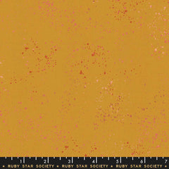Pattern of multi-colored speckles on a gold background with ruler