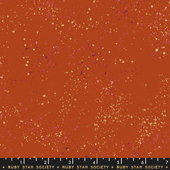Pattern of multi-colored speckles on a dark orange background with ruler