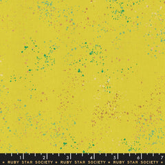 Pattern of multi-colored speckles on a yellow background with ruler