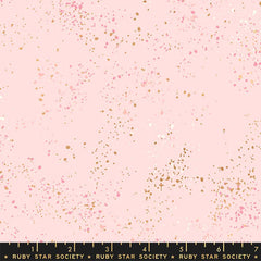 Pattern of multi-colored speckles on a light pink background with ruler