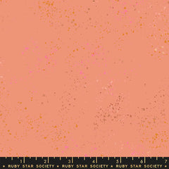 Pattern of multi-colored speckles on a peach background with ruler