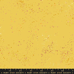 Pattern of multi-colored speckles on a yellow background with ruler