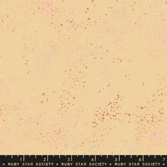 Pattern of multi-colored speckles on a beige background with ruler